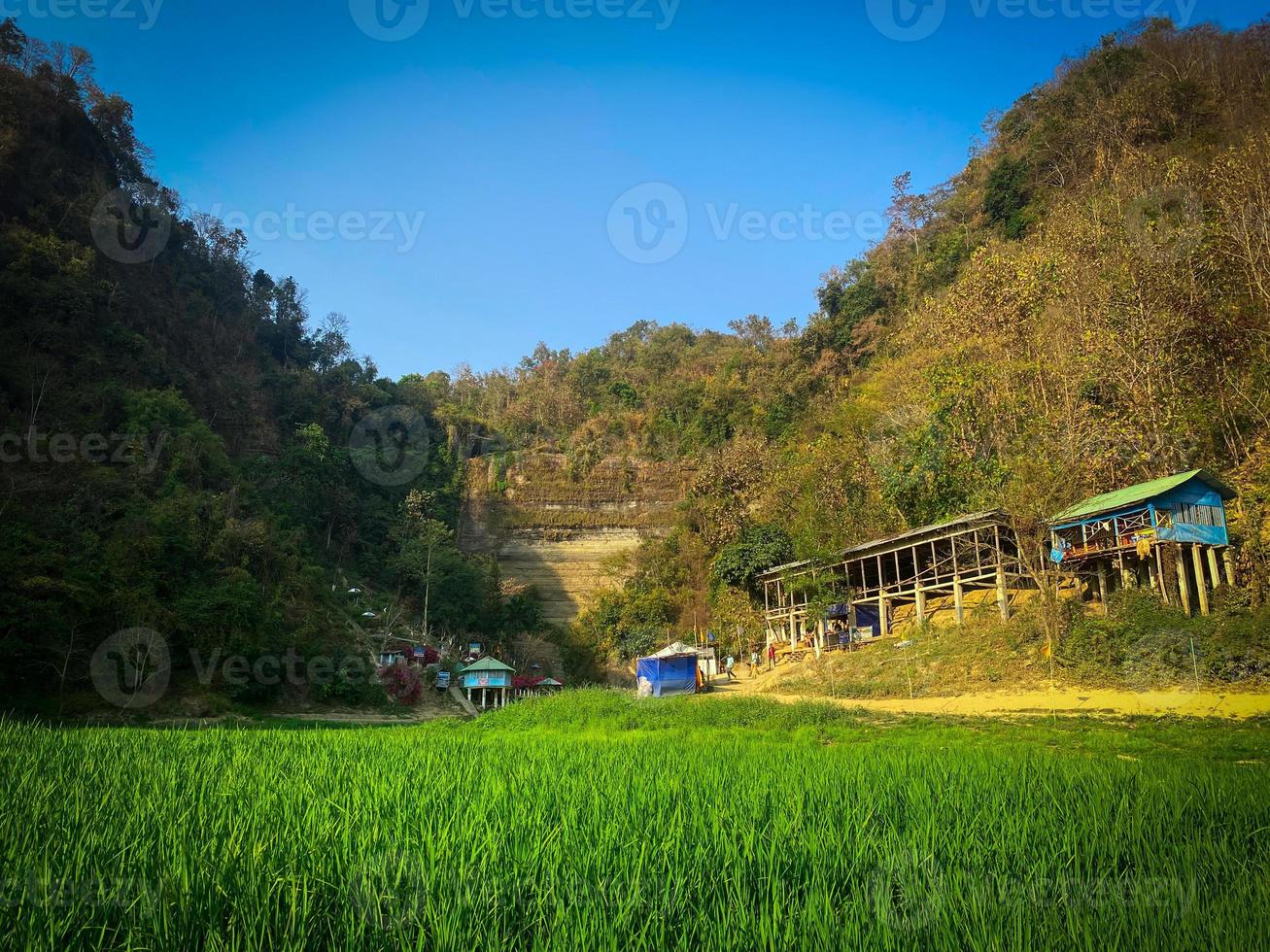 A green grass field with hills and a house in the background. photo