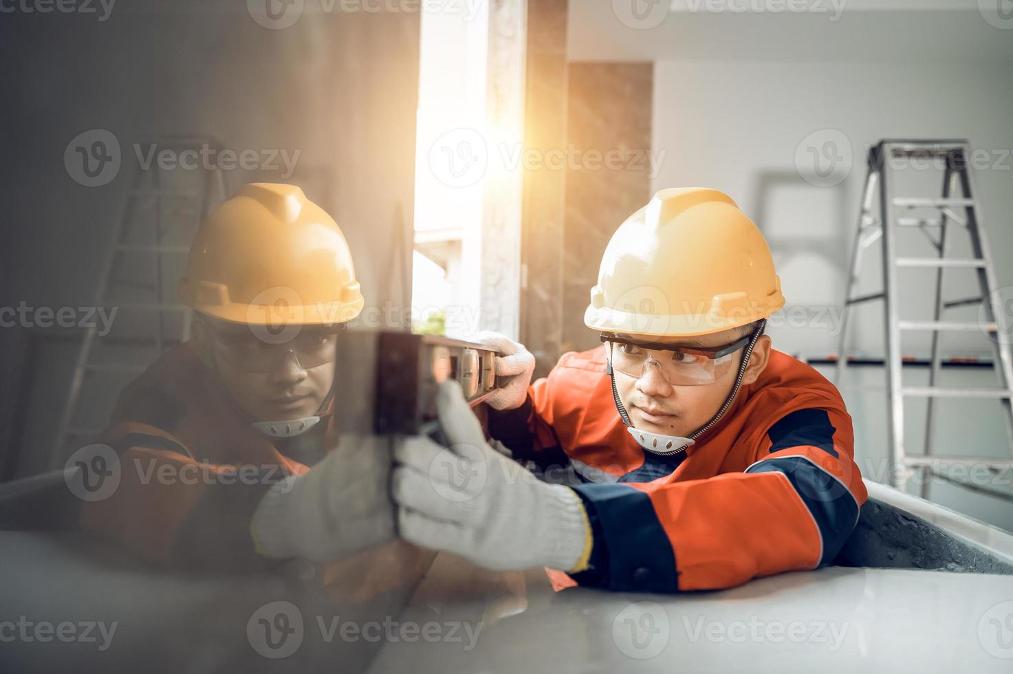 Asian worker using a level gauge to measure wall masonry working with wall concrete blocks.Engineer doing a level check on the wall at construction site photo