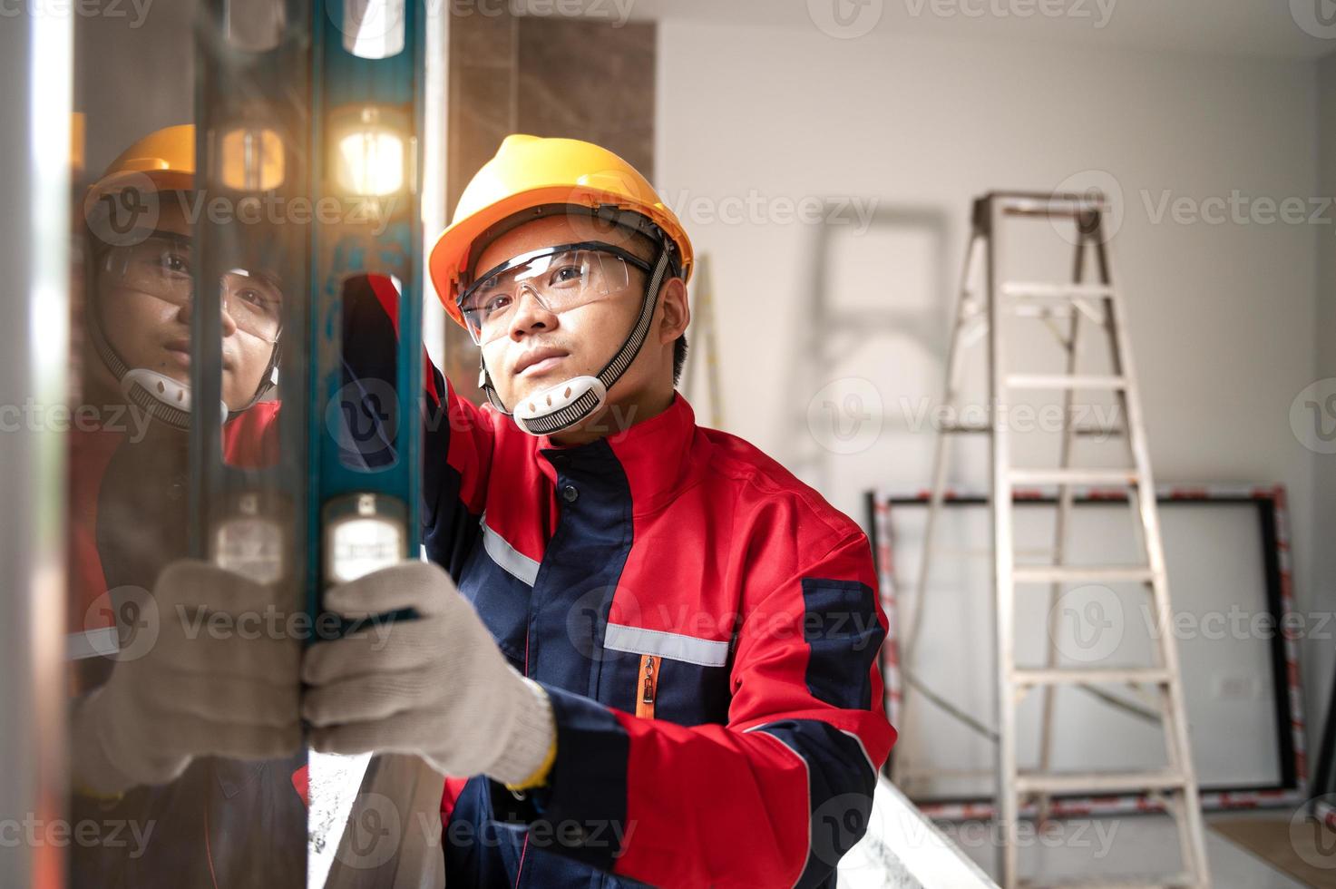 Asian worker using a level gauge to measure wall masonry working with wall concrete blocks.Engineer doing a level check on the wall at construction site photo