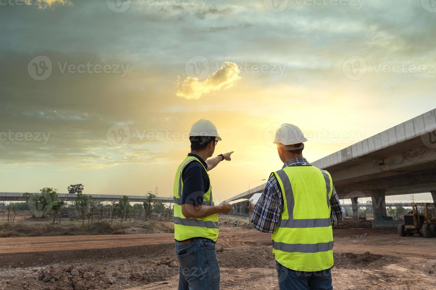 asiático arquitecto y maduro supervisores reunión a construcción sitio multiétnico trabajadores y ingenieros que se discute planes dos construcción trabajadores trabajando juntos mientras visitando Autopista construcción foto