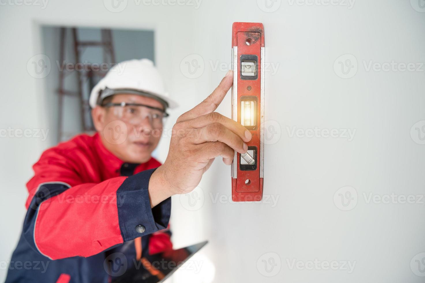 a construction worker or architect wearing a hard hat is checking the wall with a level gauge. photo