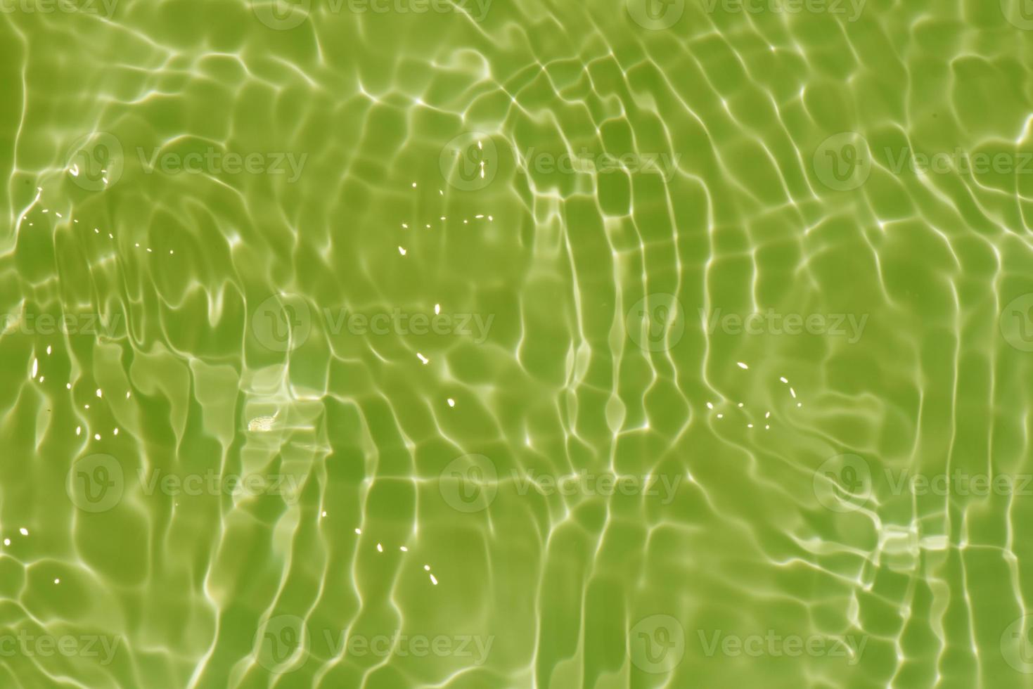 Light green water with ripples on the surface. Defocus blurred transparent colored clear calm water surface texture with splashes and bubbles. Water waves with shining pattern texture background. photo