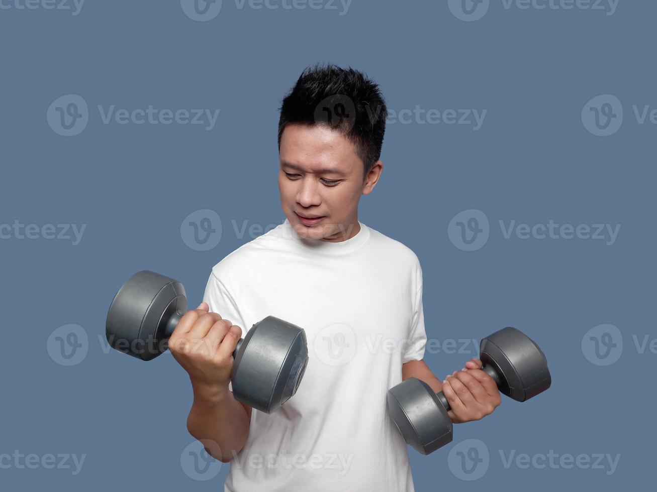 Young man doing arm exercises using dumbbells isolated on plain background photo