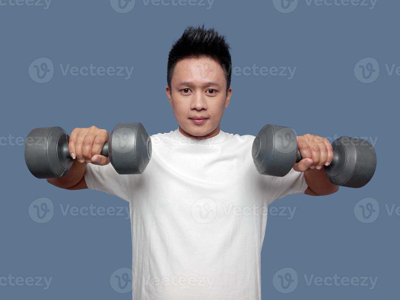 Young man is exercising using dumbbells in both hands photo