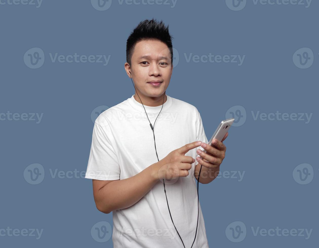 Man holding cell phone and using earphones looking at camera photo