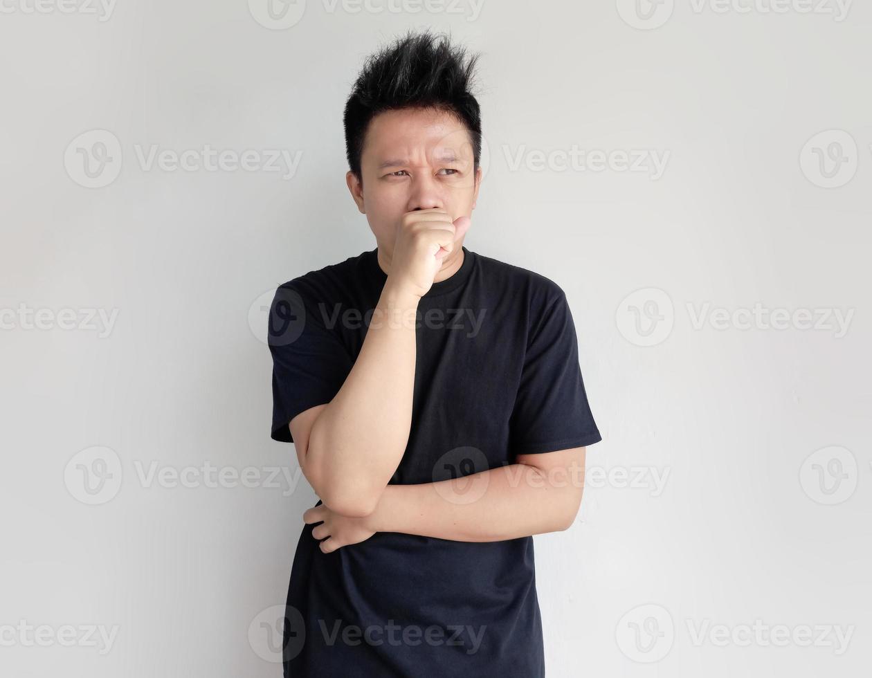 Young man with black t shirt covers his mouth with his hand photo