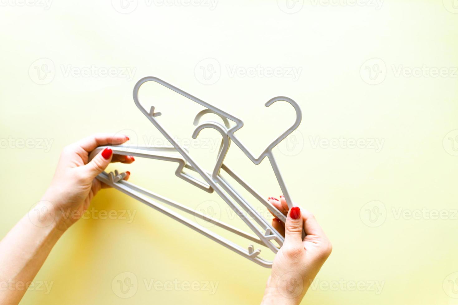 Hands holding hangers on yellow background photo