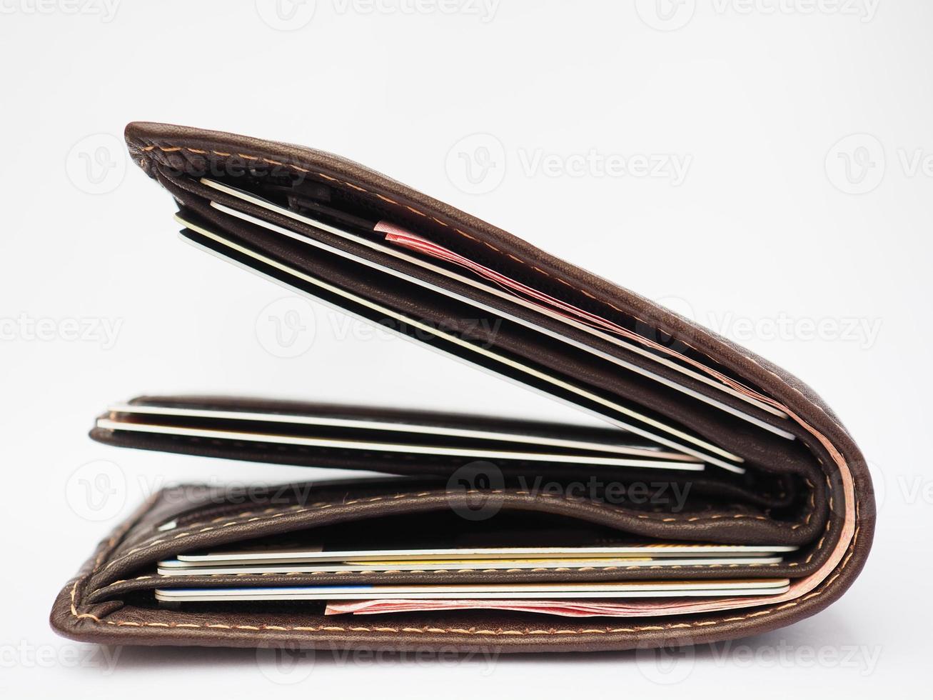 brown leather wallet full of credit cards and red bank notes on white background photo