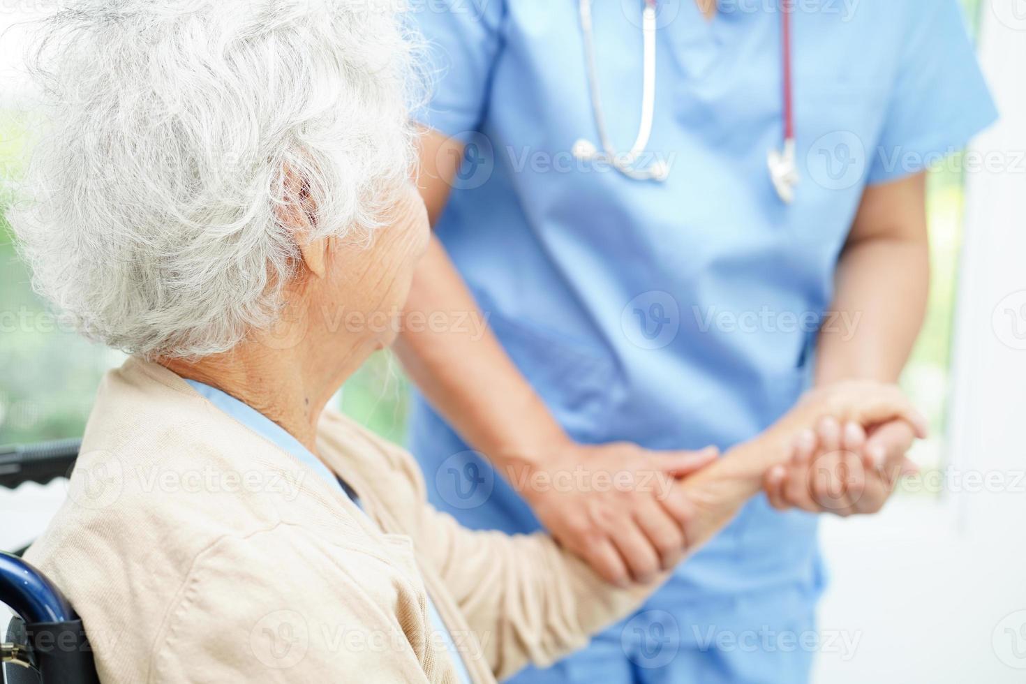 médico tomados de la mano paciente anciana asiática, ayuda y atención en el hospital. foto