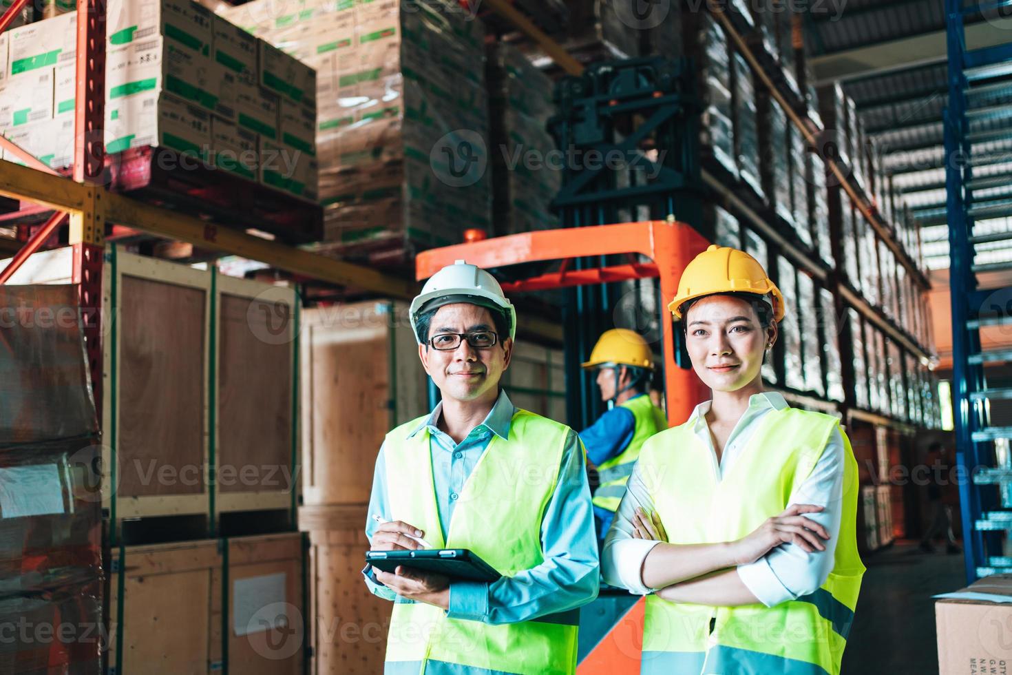 Working at warehouse. asian woman warehouse worker and Manager Shows Digital Tablet Information to further placement in storage department. In Background Stock of Parcels with Products photo