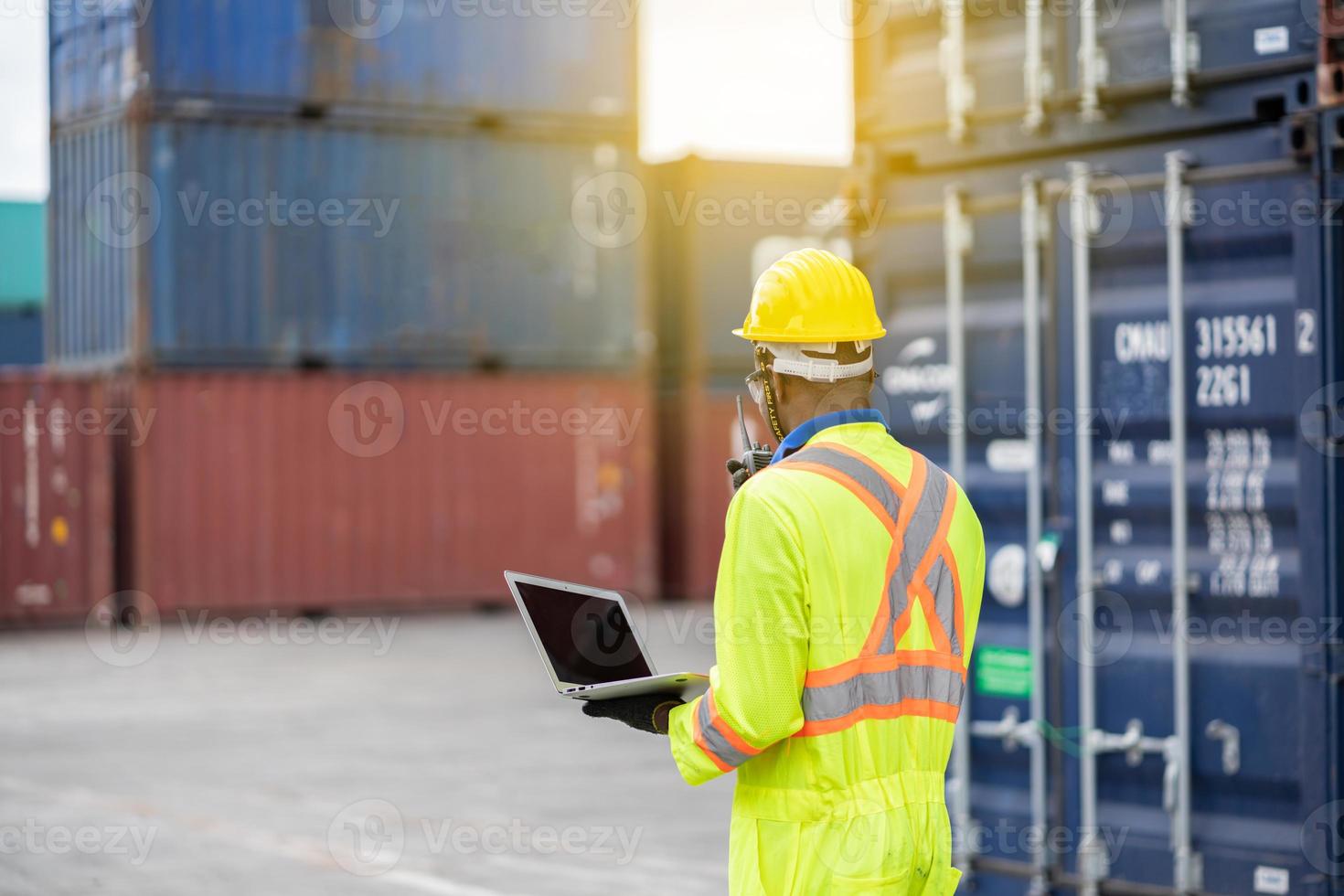 Worker man in protective safety jumpsuit uniform with yellow hardhat and use  Walkie Talkie check container at cargo shipping warehouse. transportation import,export logistic industrial service photo