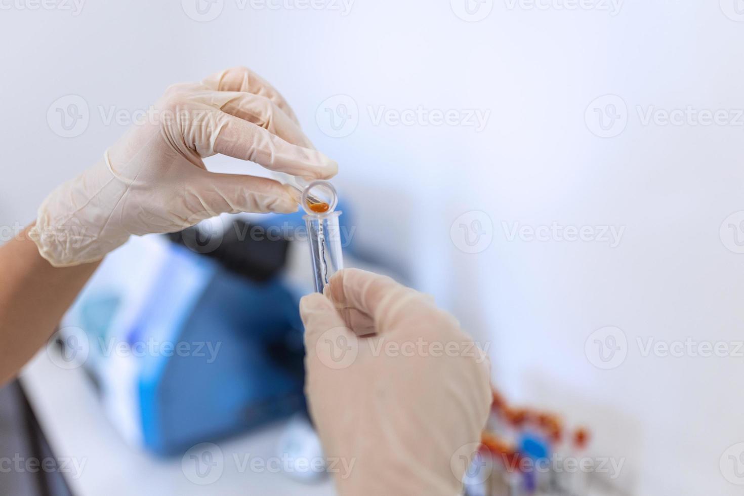 Scientific laboratory technician pipetting in research lab. Macro shot. Dripping reagent into test tube with sample, closeup. Laboratory analysis photo