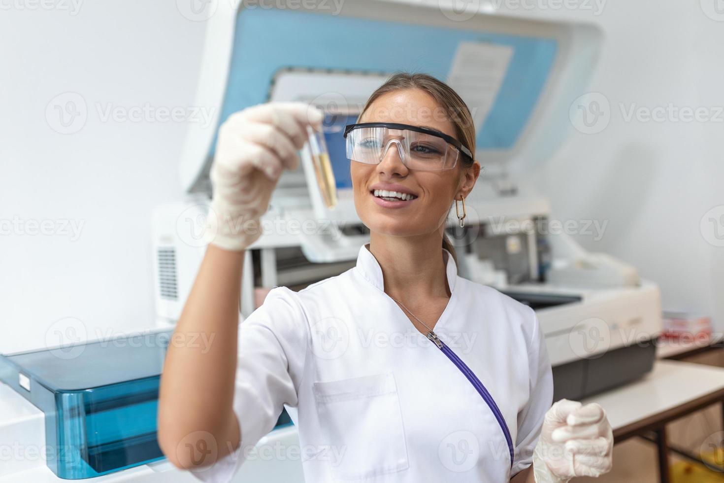 Close up of young doctor in biochemistry analysing and holding test tube with sample of genetic material. Chemistry researcher in sterile laboratory using modern technology to test microbiology liquid photo