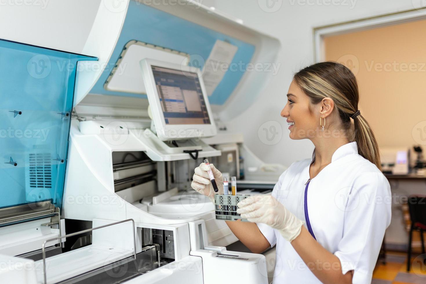 retrato de un joven hembra laboratorio asistente haciendo análisis con prueba tubos y analizador máquinas sentado a el moderno laboratorio foto