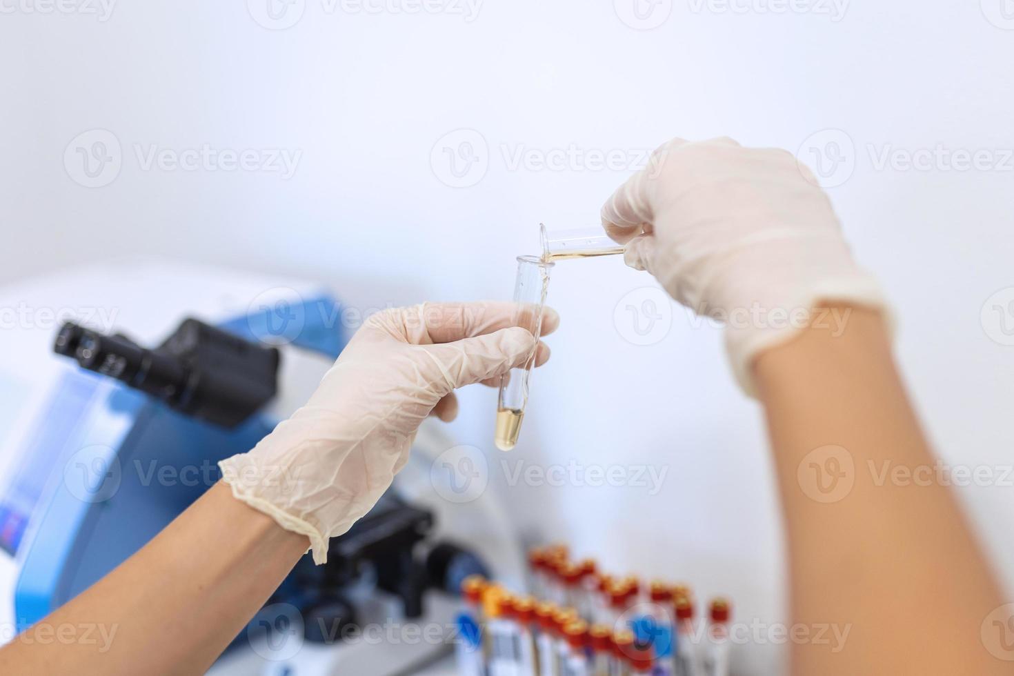 Scientific laboratory technician pipetting in research lab. Macro shot. Dripping reagent into test tube with sample, closeup. Laboratory analysis photo