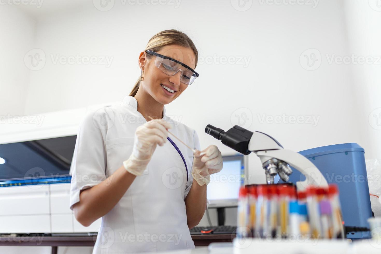 Woman biologist using micro pipette with test tube and beaker for experiment in science laboratory. Biochemistry specialist working with lab equipment and glassware for development. photo