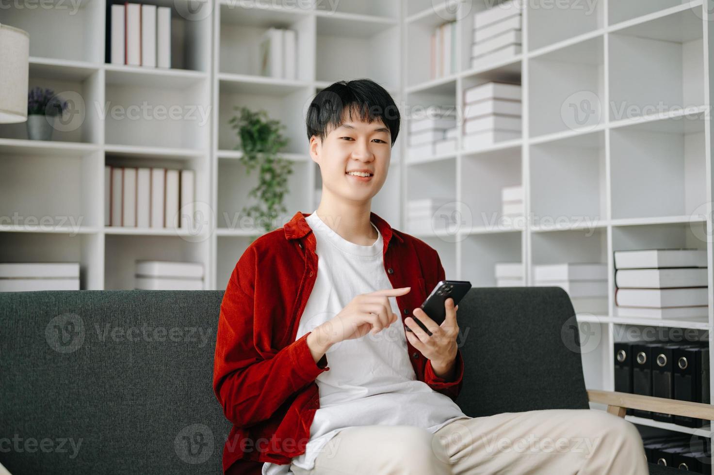 joven atractivo asiático hombre sonriente pensando planificación escritura en computadora portátil, tableta y ordenador portátil trabajando desde hogar a hogar oficina foto