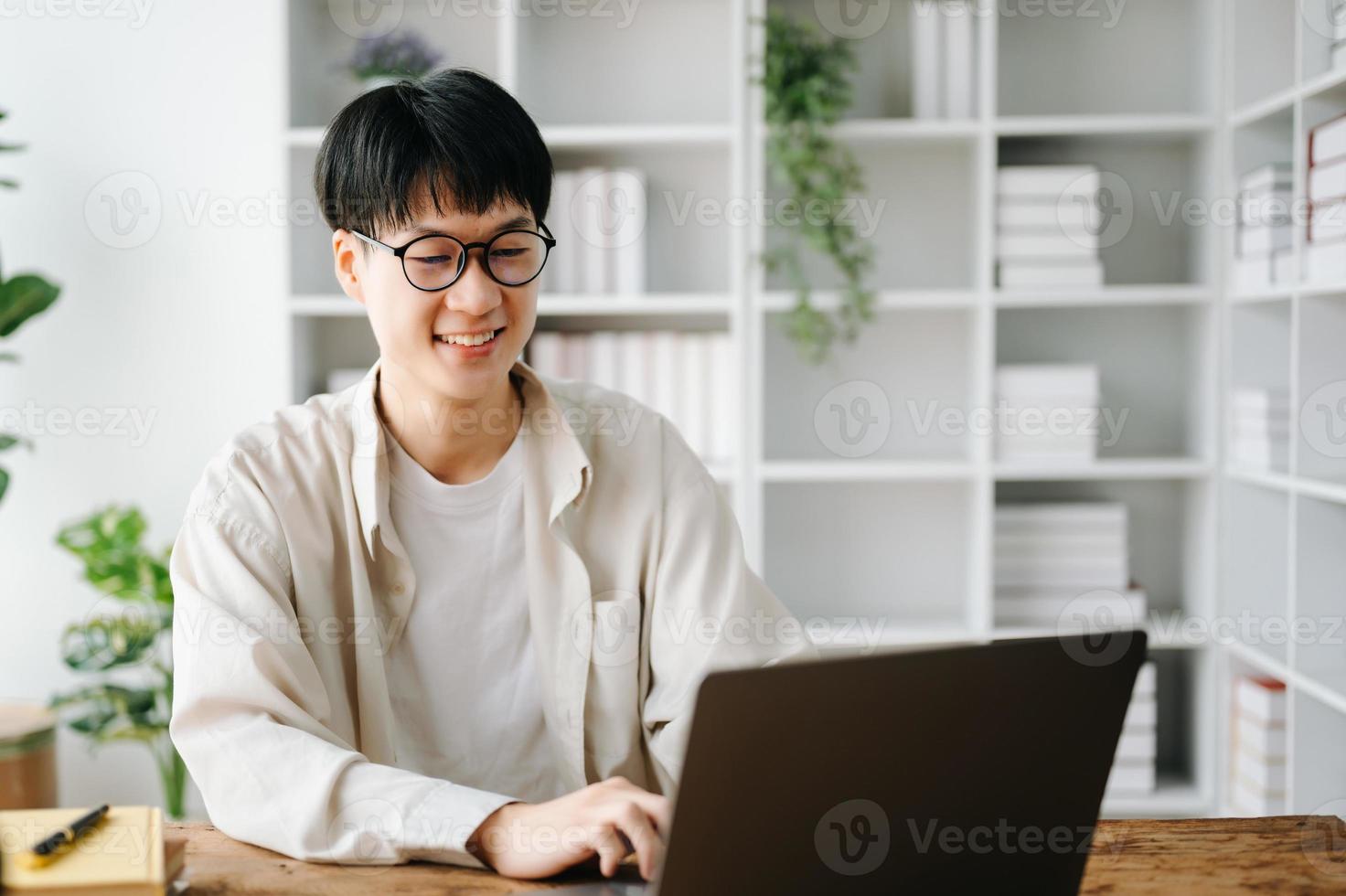 hermoso y talentoso joven asiático hombre estudiante trabajando en su proyecto asignación, utilizando ordenador portátil y tableta a buscar un en línea informaciones foto