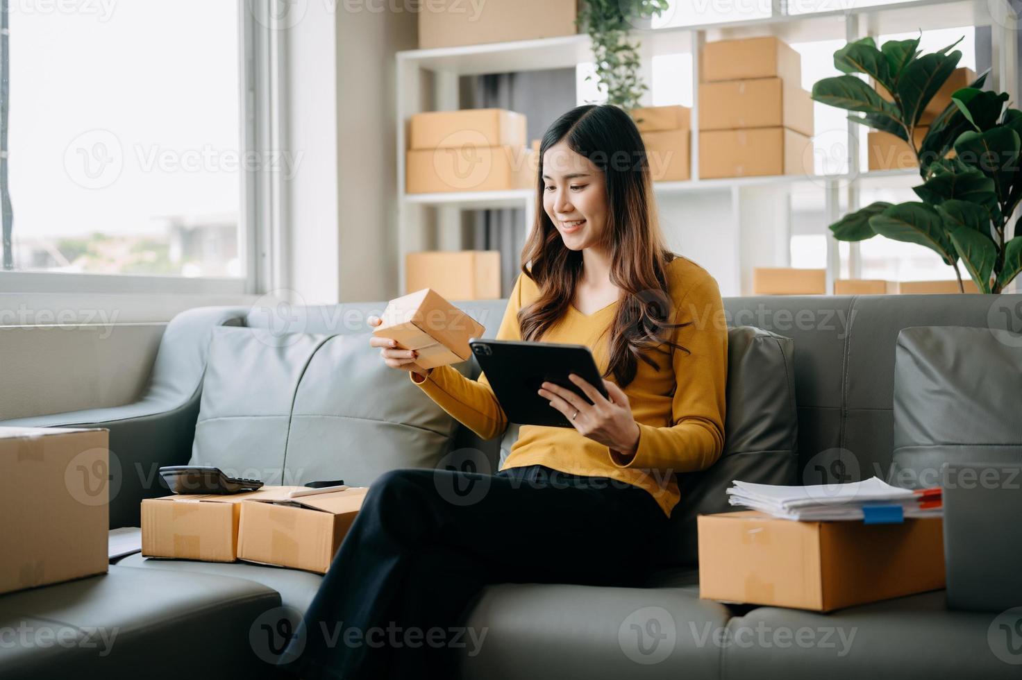 Young asian business owner woman prepare parcel box and standing check online orders for deliver to customer on tablet, laptop Shopping Online concept. photo