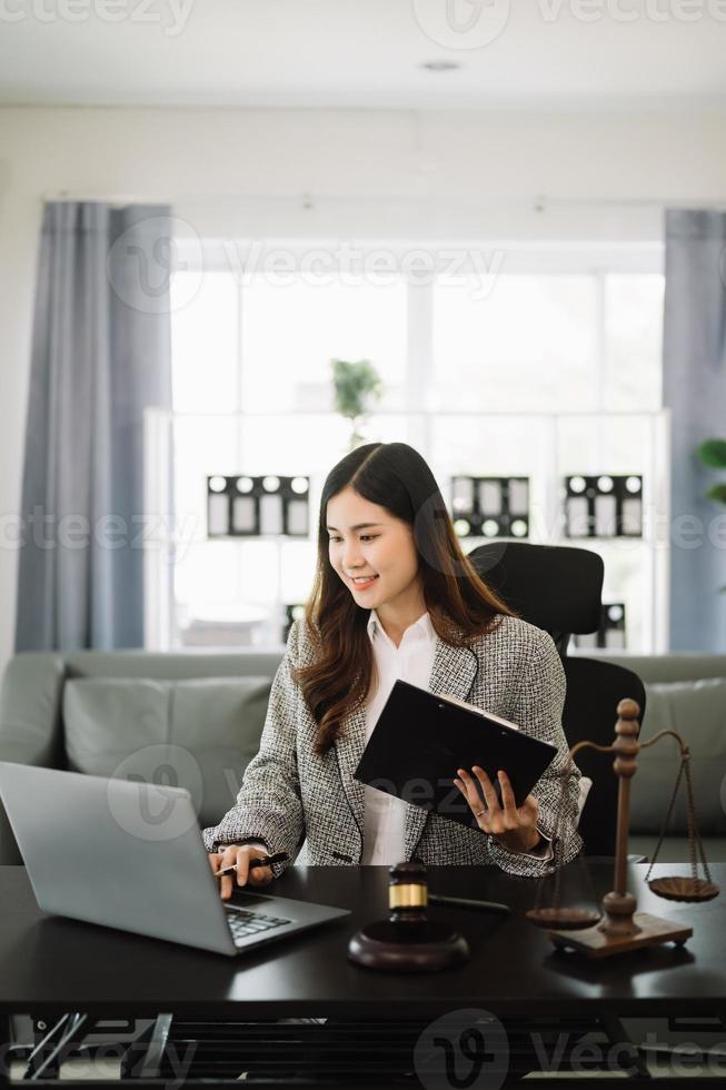 hermosa asiático mujer abogado trabajando y mazo, tableta, ordenador portátil en frente, Consejo justicia y ley concepto. en oficina foto