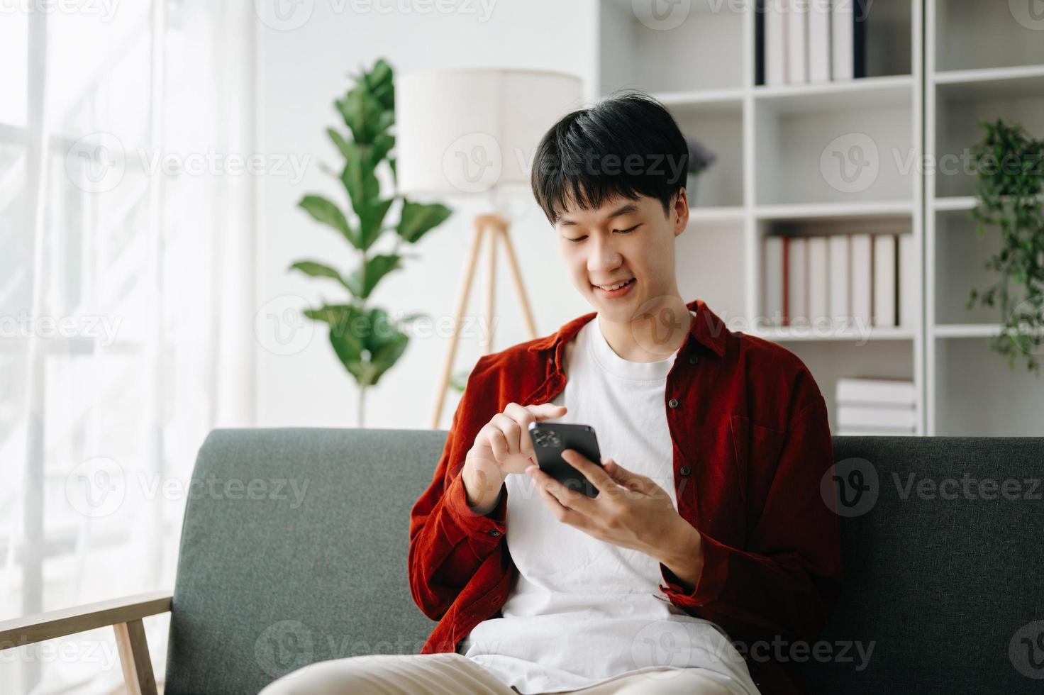 Young attractive Asian man smiling thinking planning writing in notebook, tablet and laptop working from home  at home office photo