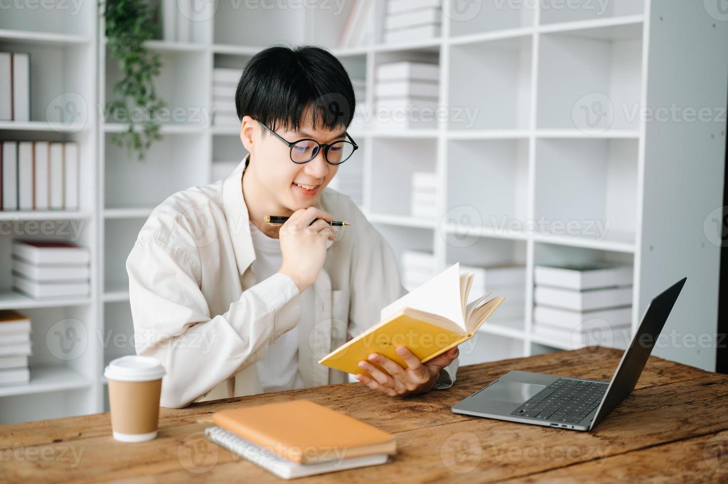 hermoso y talentoso joven asiático hombre estudiante trabajando en su proyecto asignación, utilizando ordenador portátil y tableta a buscar un en línea informaciones foto