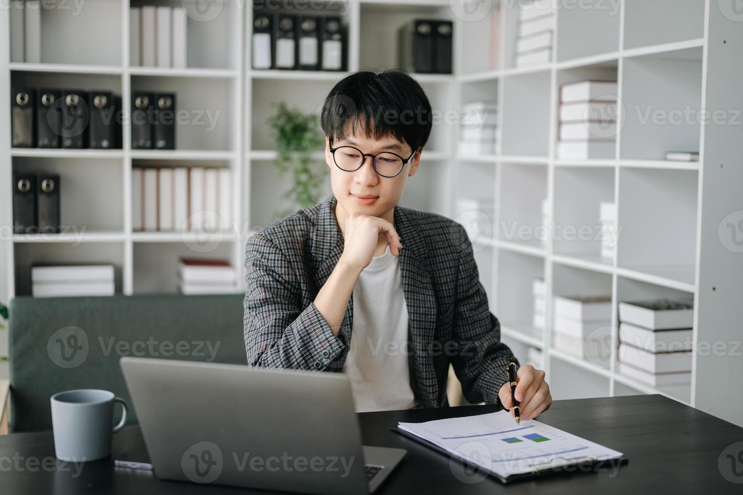 Young business man executive manager looking at laptop watching online webinar training or having virtual meeting video conference doing market research working in office. photo