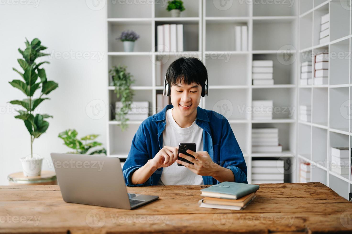 masculino estudiante tomando notas desde un libro a biblioteca, joven asiático sentado a escritorio haciendo asignaciones en Universidad biblioteca foto