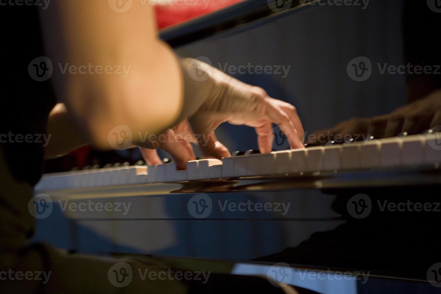 close-up on the hands of a woman playing the piano with music keys photo