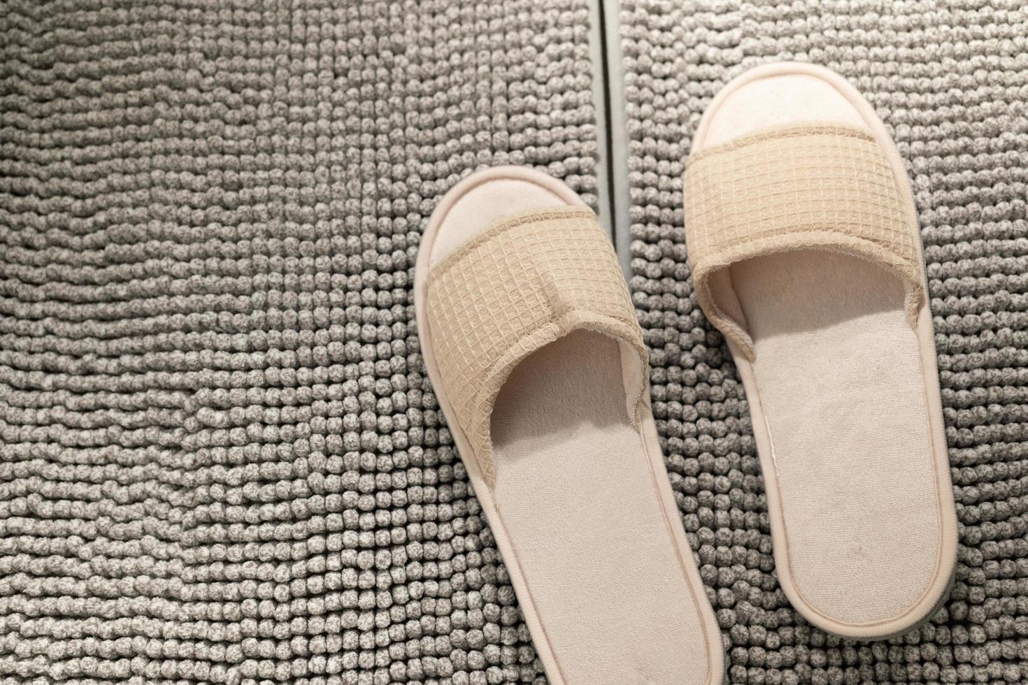 Slipper on the carpet at home. slippers from hotel, airplane are on white floor, home slippers, home footwear. Clear warm domestic sandal. photo