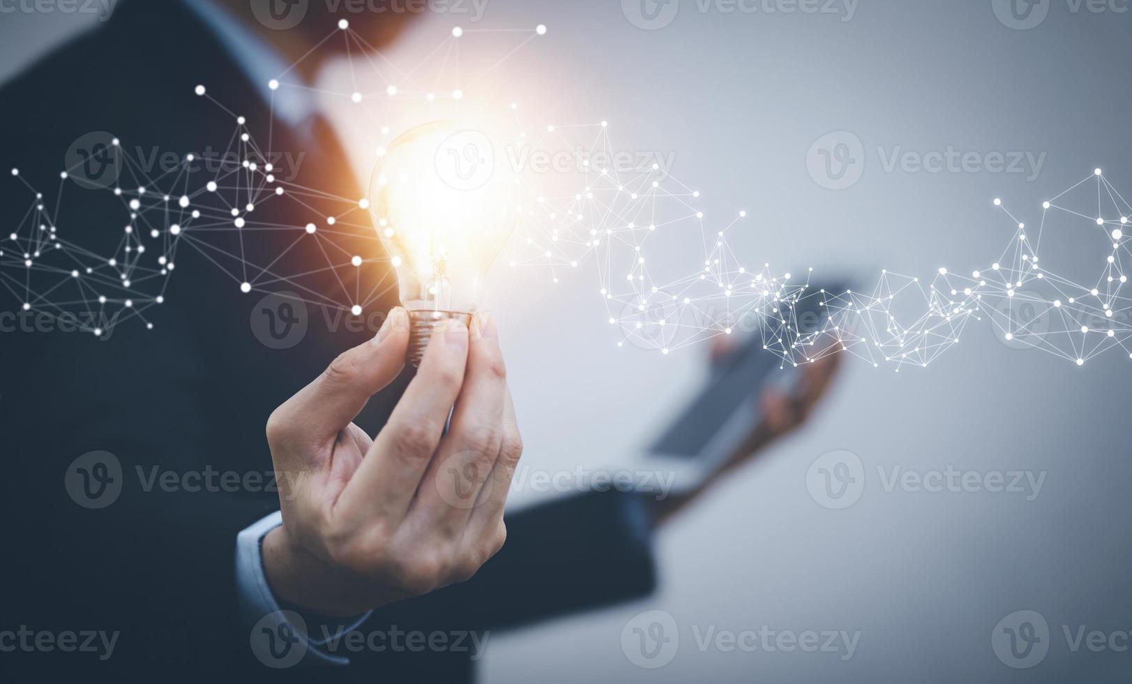 Businessman hand holding light bulb with icons and working on the desk, Creativity and innovation are keys to success.Concept of new idea and innovation with energy and power , working at home, photo