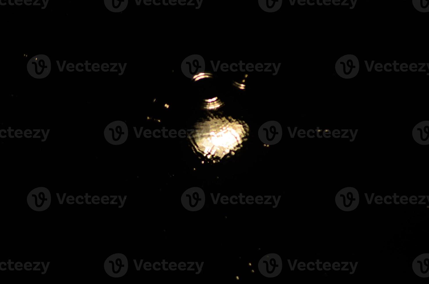 Light is reflected in a puddle. Blurred light in the puddle, dark night. Splashes. photo