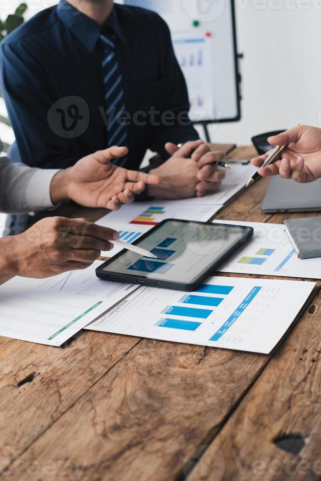 Group of young business people working and communicating while sitting at the office desk together, using tablet to present their concept. photo