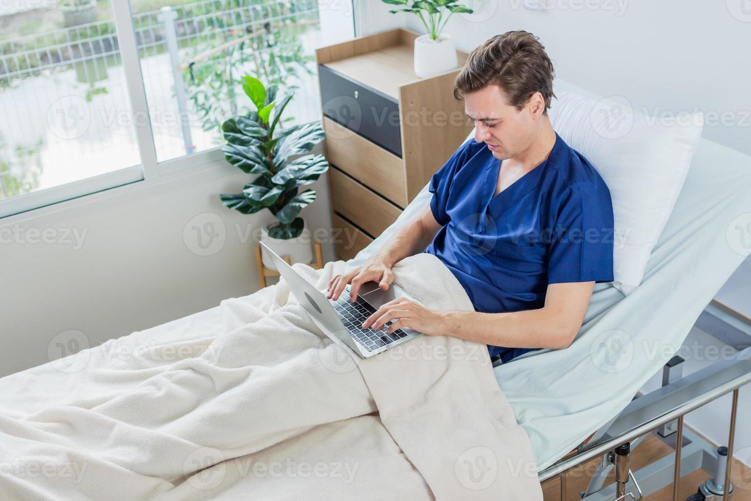 Caucasian patient using laptop in hospital room. man sick patient lying