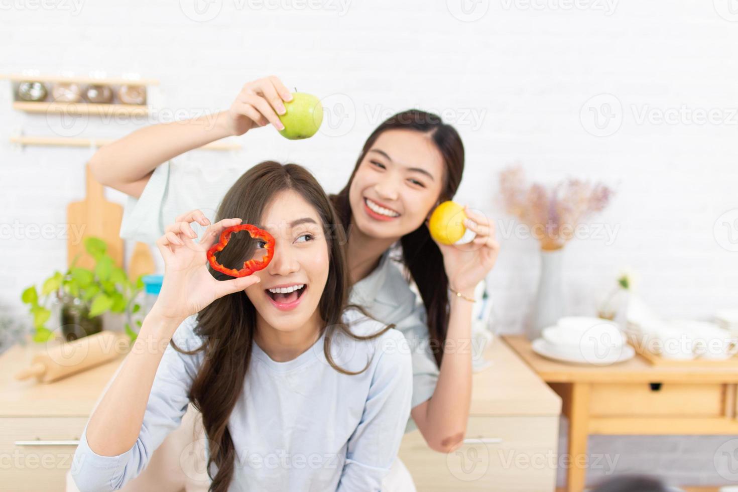 Asian two women wearing  sportswear eat healthy foods in kitchen. Young beautiful girl  happy and enjoy eating fruits healthy foods. photo