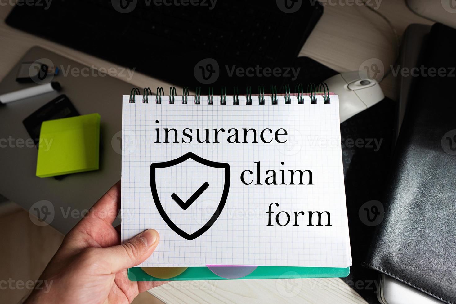 Insurance claim form word on notebook holding man against desktop. photo