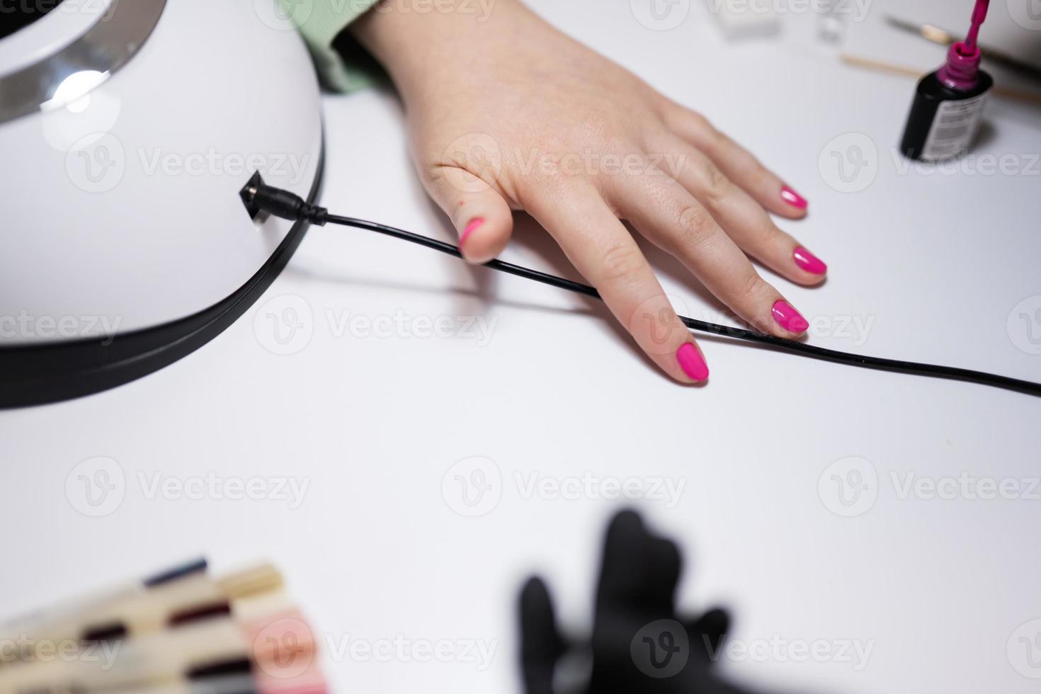 Top view of manicure master working with female client in beauty salon. Manicurist makes woman nail. photo