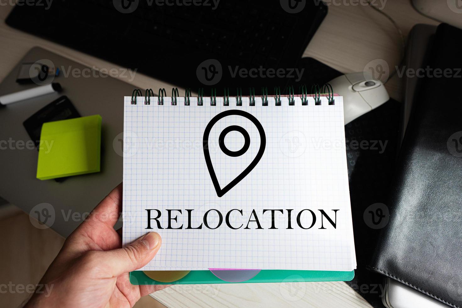 Relocation word on notebook holding man against desktop. photo