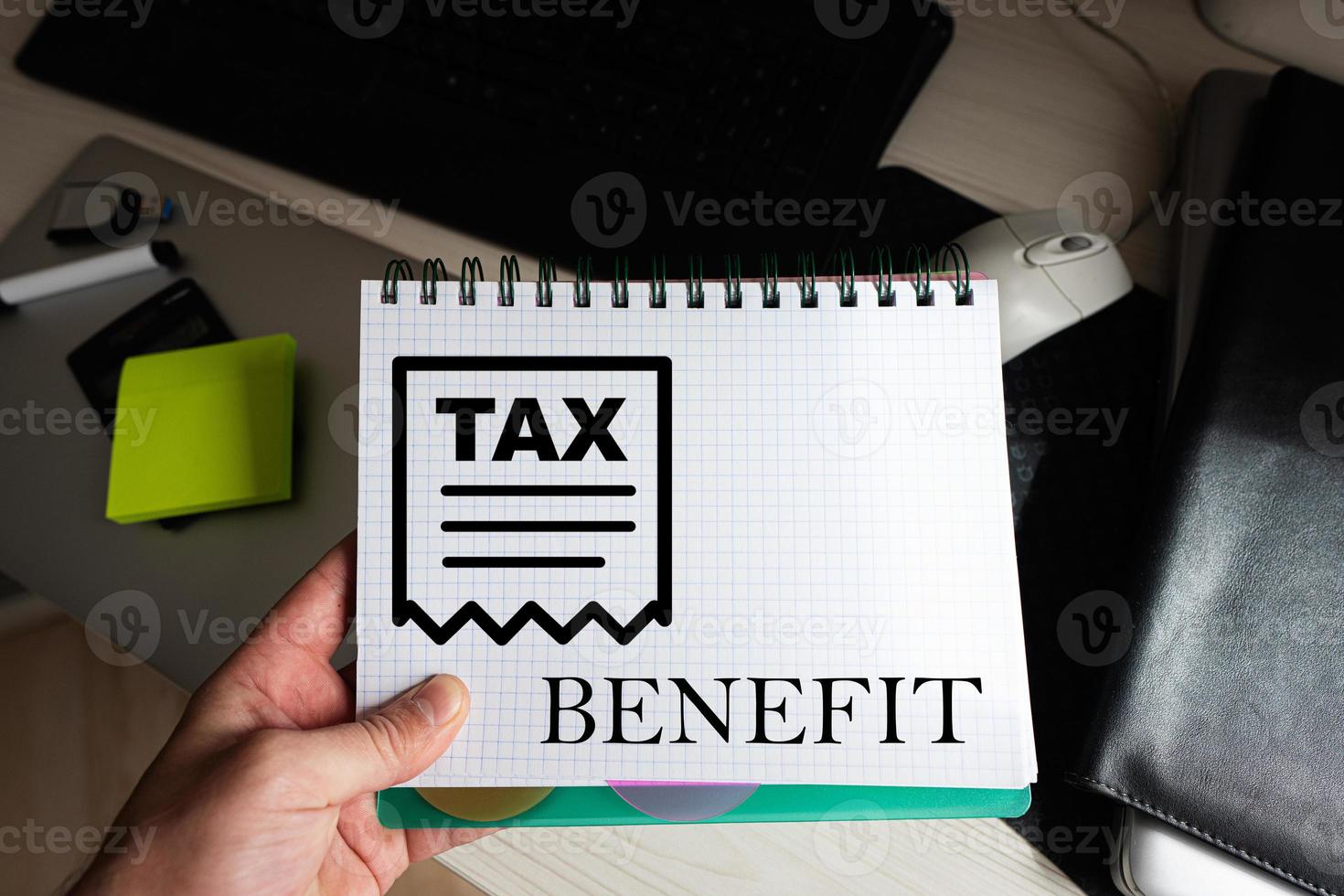 Tax benefit word on notebook holding man against desktop. photo