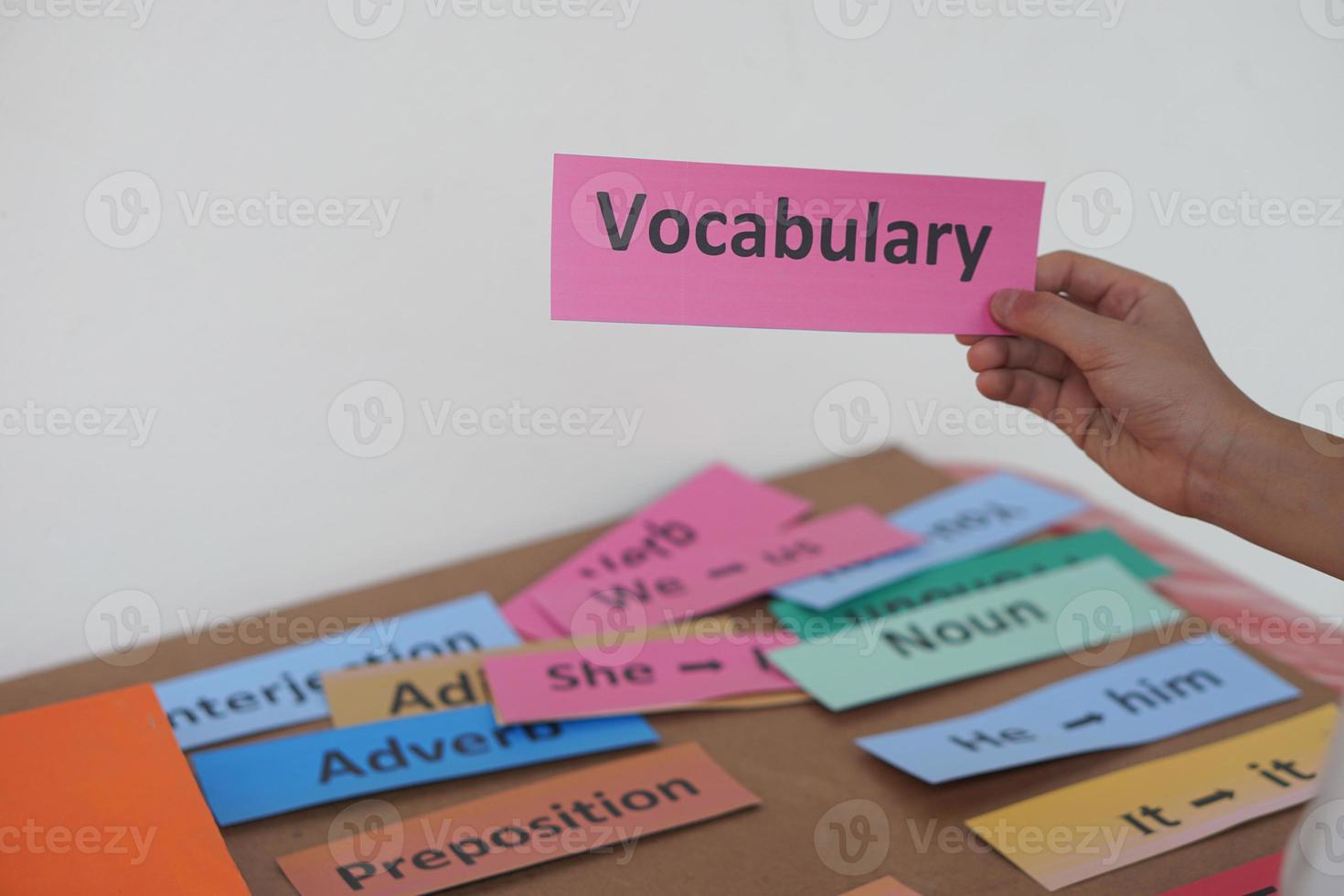 Closeup student's hand hold English vocabulary word card. Concept, education, learning, studying language. Education. Reading and memorizing strategy of learning process for kid. Practice make perfect photo