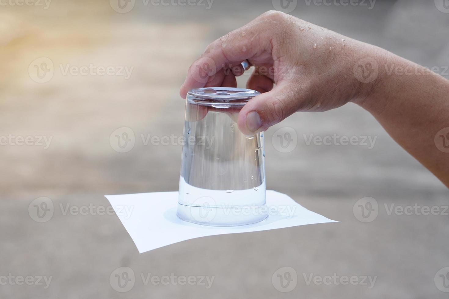 Closeup hand hold and turn  a glass of water over down. covered the glass with paper. Concept,  science experiment about air and liquid pressure. Easy science subject activity, education. photo