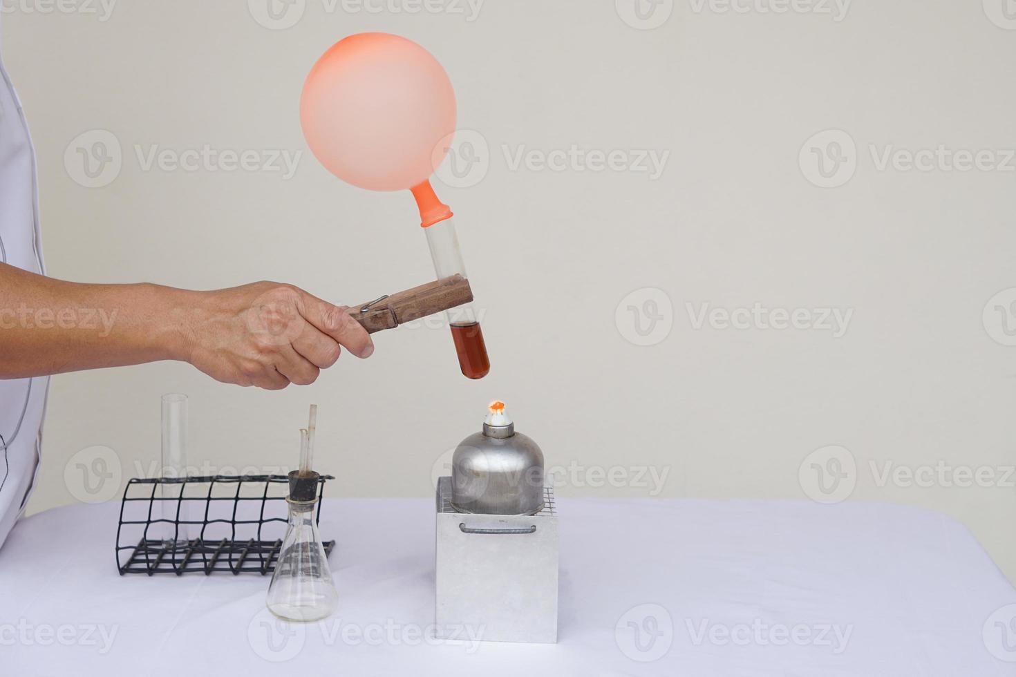 Closeup man is demostrating science exeriment about reaction of balloon on test tube is burned from lantern. The expanding of air pressure, reaction of chemical substance. Concept, Science activity. photo