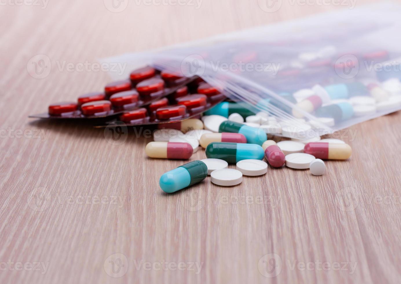 Colorful pills with capsules and pills in zip-lock plastic bags. Placed on the dispensing table, wooden background photo
