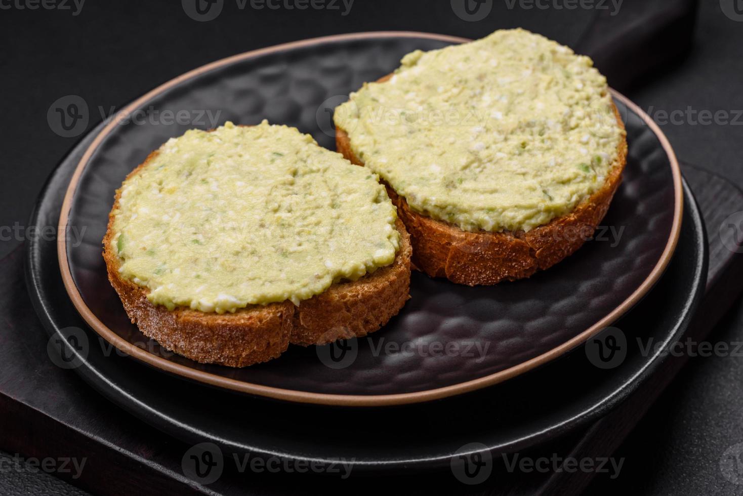 Grilled toast with avocado paste, eggs, cream cheese, salt, spices and herbs photo