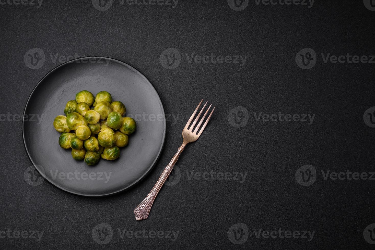 Delicious boiled Brussels sprouts on a ceramic plate on a dark concrete background photo