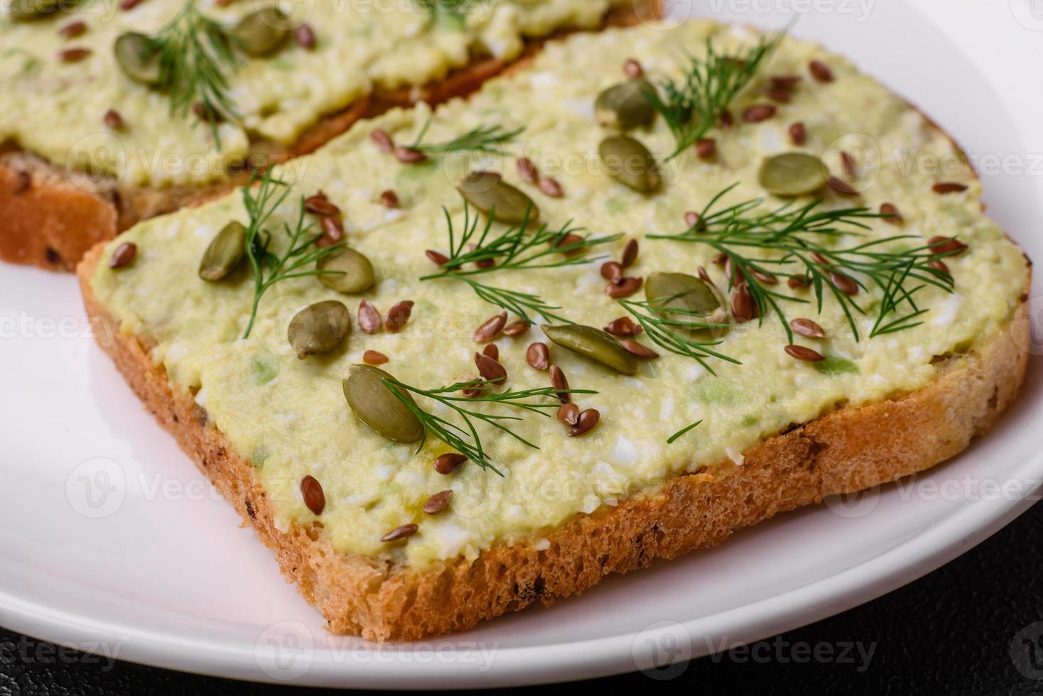 Grilled toast with avocado paste, eggs, cream cheese, salt, spices and herbs photo