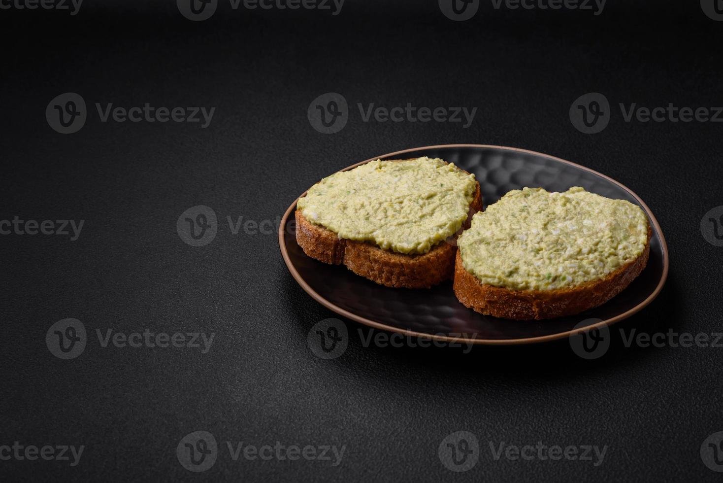 Grilled toast with avocado paste, eggs, cream cheese, salt, spices and herbs photo