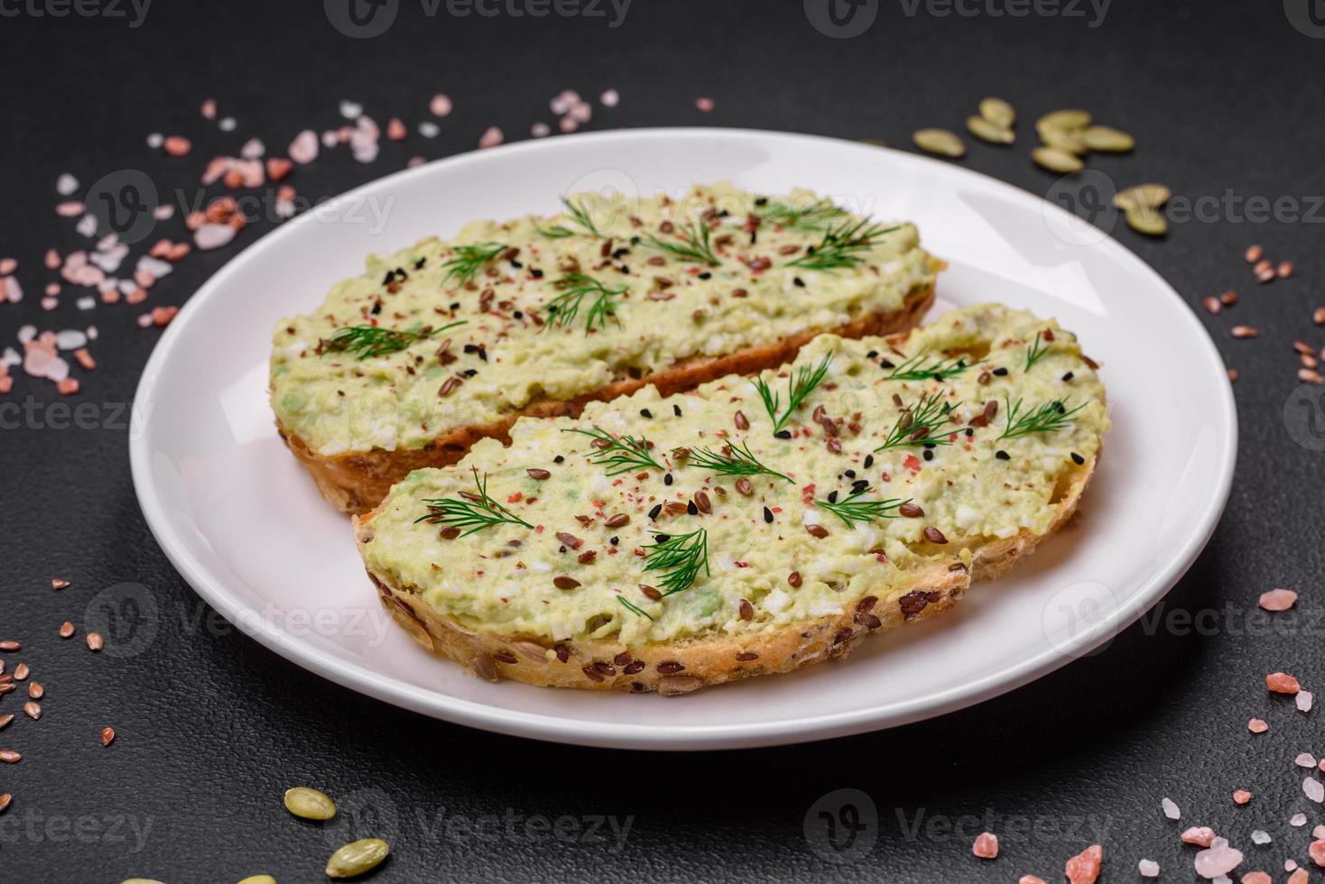 Grilled toast with avocado paste, eggs, cream cheese, salt, spices and herbs photo