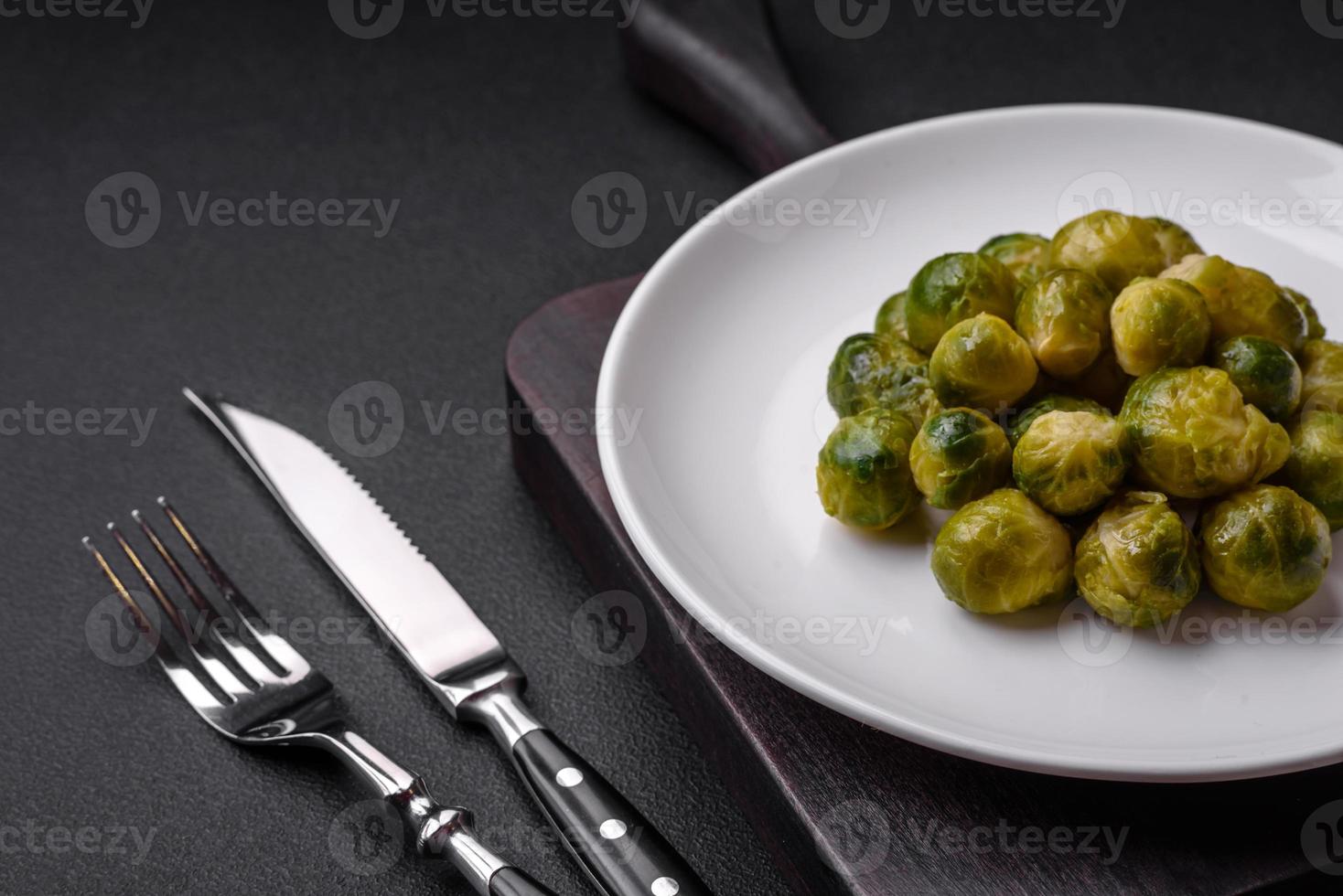 Delicious boiled Brussels sprouts on a ceramic plate on a dark concrete background photo