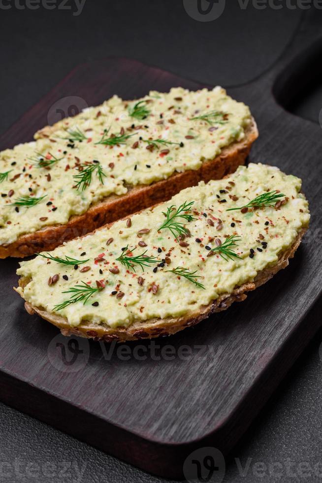 Grilled toast with avocado paste, eggs, cream cheese, salt, spices and herbs photo